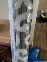 Photo of the rolled camping mat showing part of the branding text and the woven pattern under plastic shrink wrap.