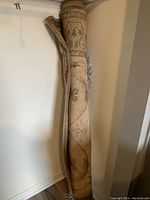 Rolled beige rug standing upright showing floral pattern partly visible