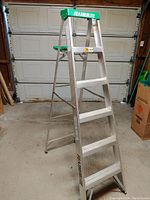 Photo showing Featherlite brand 6-foot aluminum step ladder with five steps and green top support tray, placed in a garage setting.