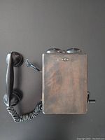 Top view of the wooden box telephone with handset resting to the side and crank visible on the right side.