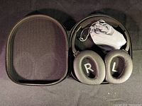 Folded black Audeara EQ headphones inside open black zippered carrying case, cushioned ear pads labeled L and R visible.
