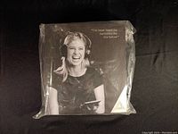 Sealed packaging of Audeara EQ headphones showing the front with a woman wearing headphones and holding a phone.