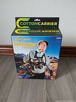 Front of box showing Cotton Carrier branding, image of man wearing the camera vest in outdoor setting.