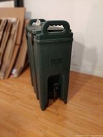 Full side view of the green rectangular thermal container showing the handle and spigot at bottom front.