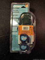 Front view of Dymo LetraTag 100H Plus label printer packaging showing label printer and included label cassettes.