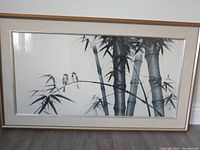 Framed Japanese ink painting of bamboo and two birds on a branch.