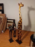 Three African decor sculptures including giraffe, female figure, and elephant visible from the front.
