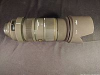 Lens with hood attached lying horizontally on black background
