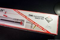 Photo of the Rubi tile cutter box showing 21-inch size, compatibility with ceramic, porcelain, and glass tile, and 2-year guarantee.