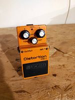 Front view angled of vintage orange Boss DS-1 distortion pedal showing knobs and branding.