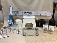 Overview of all bathroom items including shower curtain rod box at back, cordless vacuum, step stool, scale, soap dispensers, plunger and hooks.