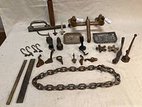 Full lot of various metal hardware laid out on a surface showing multiple hooks, two rectangular metal bars, heavy chain, different small hardware pieces, and a faucet.