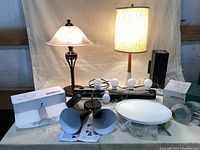 Photo of two table lamps, various light fixtures including a white round LED ceiling light, and boxed items.