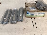 Box of 500 Sandbaggy square top sod staples with several staples outside the box for scale, all appear unused and in original packaging.
