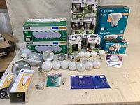 Wide shot of assorted packaged and loose light bulbs, with brand names visible including Ecosmart, GE, Sylvania.