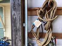 Rope coiled and hung on a wooden beam inside a structure, giving a sense of thickness and texture.