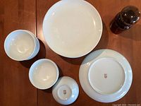 Top view showing the small cereal bowls, dinner plates stacked, and the amber pharmacy container on a wooden table.
