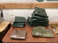 Photo showing folded green and brown tree watering bags stacked on a wooden surface.