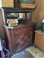 Front view of antique solid oak cabinet with upper mirror, shelf, drawer missing handle, and lower cabinet door with key.