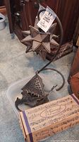 Metal star candle holder on curved base next to metal wall decor and wind chime box