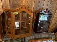 Image of both display cabinets side by side against a wooden paneled wall, showing overall condition and size comparison.