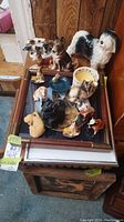 Photo of various dog figurines placed on top of framed picture and boxes, showing size variation and grouping.
