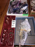 Overview image showing assorted flatware in plastic bags, wrapped antique wood spoon, napkin rings on red tray.