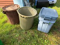 Overview image showing two garbage cans and two storage bins outdoors on grass, illustrating scale and condition