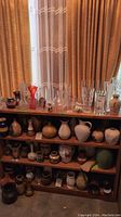 Overview of multiple shelves with various glass, ceramic and pottery vases of different sizes and styles arranged by shelf