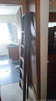 Side-angle photo of wooden step ladder leaning against wall indoors.