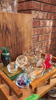 Tray with assorted glass art including green bud vase, red signed cat, clear glass caterpillar, fish figurines, and a small crystal bowl.