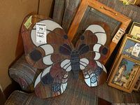 Butterfly stained glass art showing overall piece resting on a chair with visible multi-colored glass sections and metal leading.