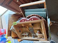 View of various wall decor items including carved wood miniature room scenes and decorative plates stacked and arranged on a surface.