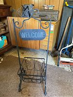 Full front view of black metal welcome sign stand with planter basket showing decorative scrollwork and welcome sign.