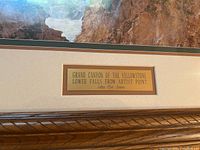 Close up photo of title plaque on the frame, identifying the artwork as 'Grand Canyon of the Yellowstone Lower Falls from Artist Point' by John Clef Jones.