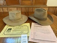 Two beige Barons Hollywood hats displayed on a wooden table with Certificate of Authenticity and paperwork.
