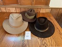 Three cowboy hats placed on wooden table, showing color and overall condition