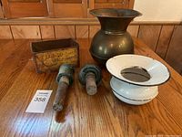 Photo showing the full lot including glass insulators, brass vessel, enamel spittoon, and metal tin box arranged on wooden table.