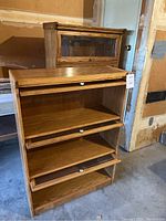 Full frontal view of the smaller library cabinet showing open three-tier compartments with glass fronts and white knob handles.
