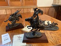 Three miniature bronze sculptures arranged on wood table