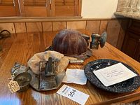 Overview image showing all items on a wooden table including hard hat, soft cap with lamp, match safe, identification plate, and notes.