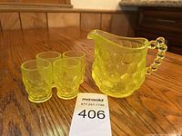 Yellow hobnail glass child’s pitcher and four glasses on a wood table with auction lot number in view.