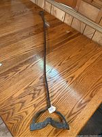 Full view of long iron cooking tool lying on wooden surface