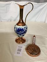 Dutch ewer combining brass, copper, and Delft porcelain with blue floral hand painting, and small copper thermometer pan with embossed Dinant scene.