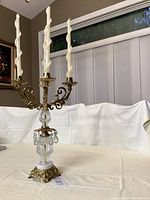 Front view of vintage 4-candle candelabra with twisted white candles on top, detailed brass arms, crystal body, and square base.