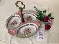 Top view of the three-compartment porcelain dish with pink floral pattern and gold trim, featuring a central metal handle.