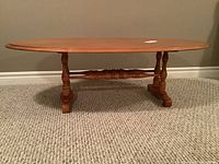 Front view of the oval hardwood coffee table showing turned legs and stretcher base.