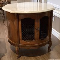 Front view of fruitwood cabinet with metal grille doors and white marble top