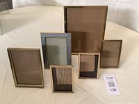Six vintage brass coloured metal photo frames arranged on table, showing various sizes and styles.