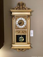 Full view of the Syroco wall clock showing the decorative top, clock face, and pendulum window.